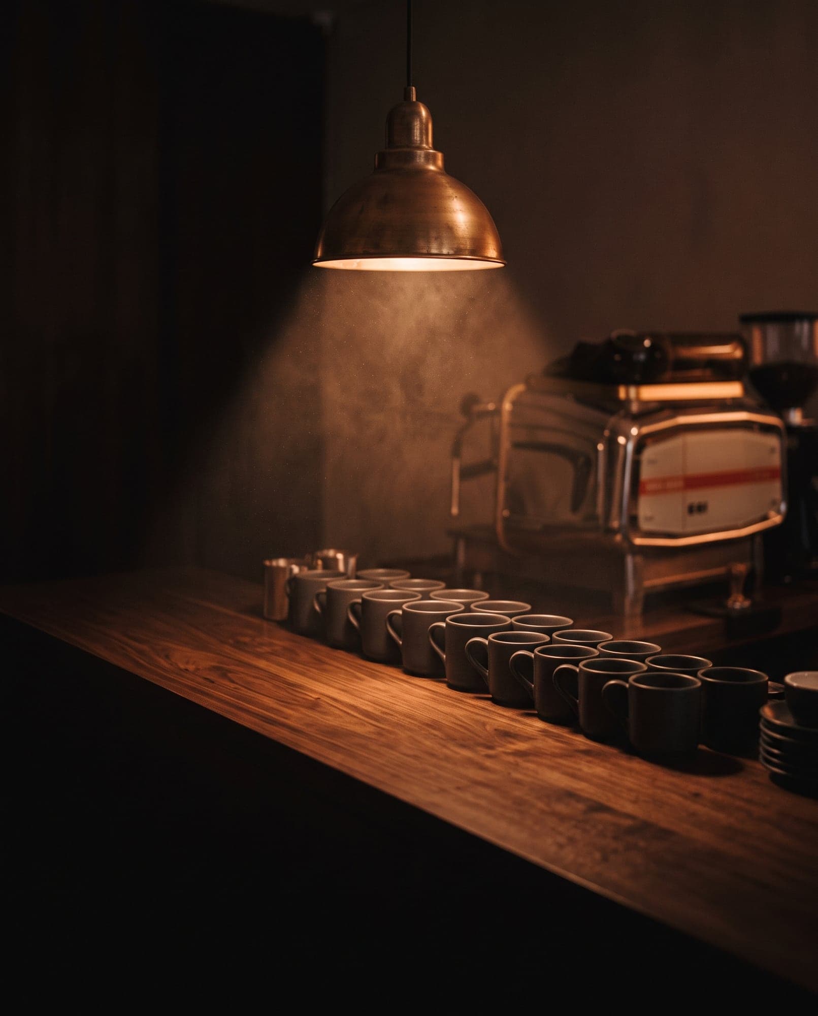 La barra de Café Nómada iluminada por una lámpara cálida, con tazas alineadas.